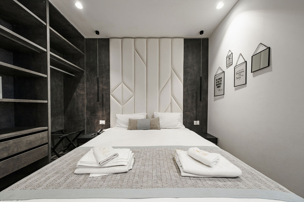 Chambre King avec tête de lit géométrique blanche et dressing ouvert à l'Hotel Kikar Netanya